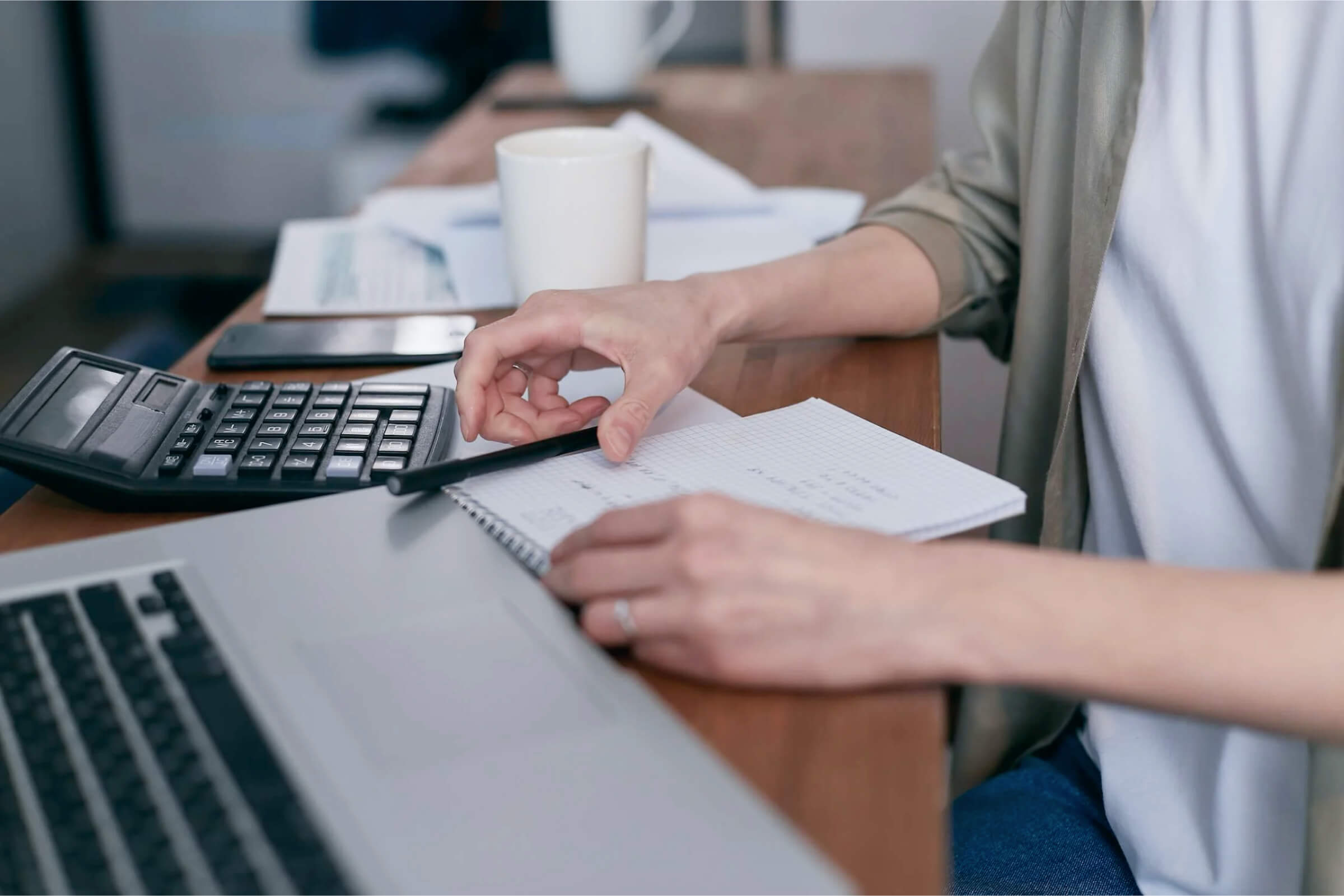 Eine Person sitzt mit Taschenrechner mit Stift und Papier